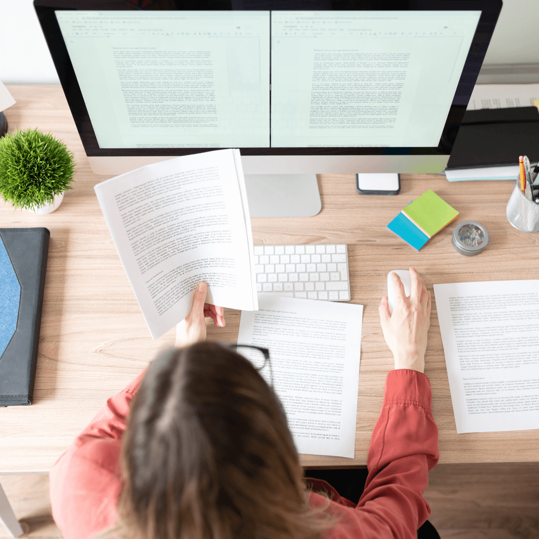 Person reviewing documents at a desk with a computer, representing Aptimized's focus on detail-oriented solutions.