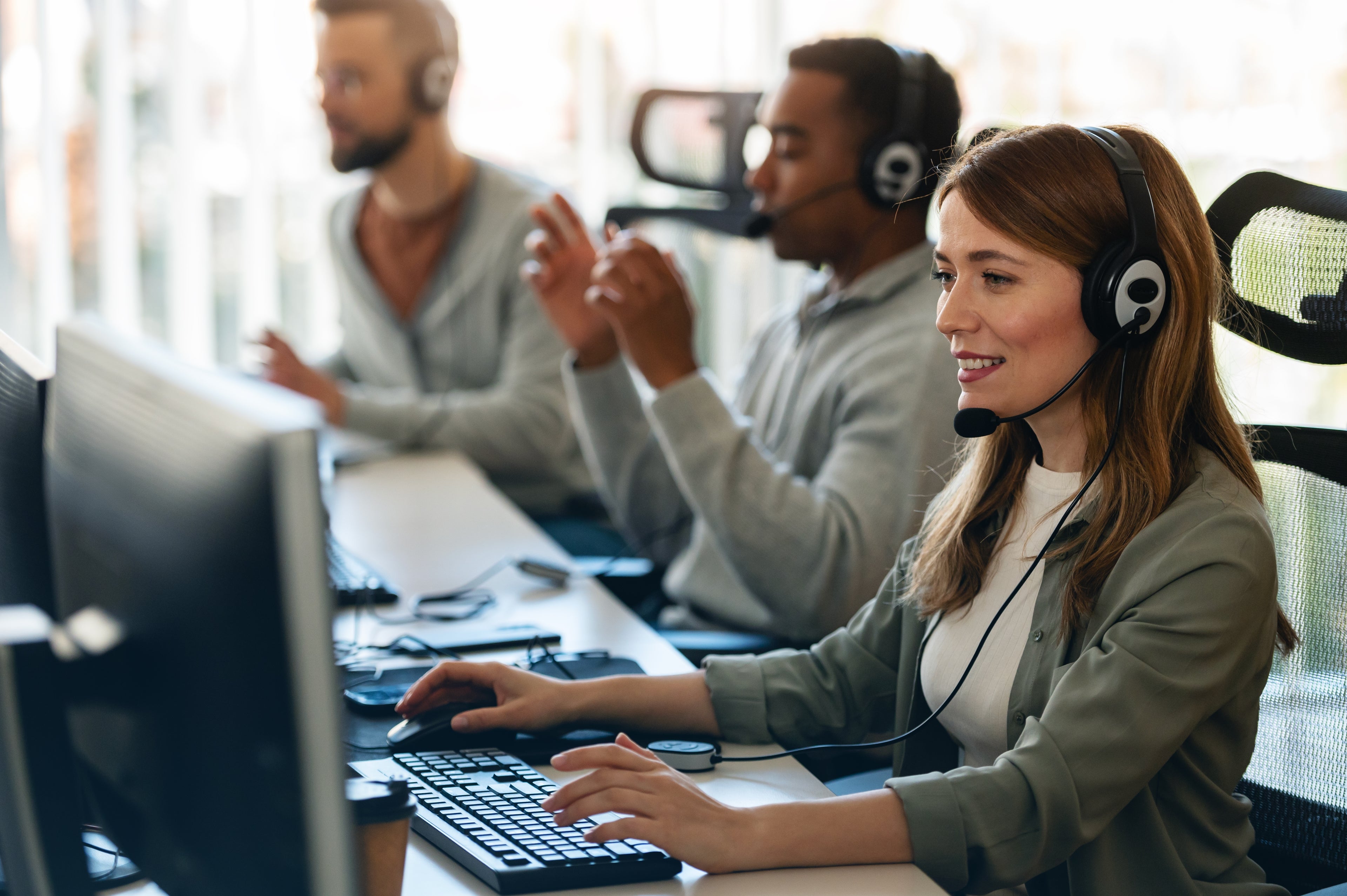 The image shows a call center team wearing headsets and working at computers, emphasizing customer support and teamwork.