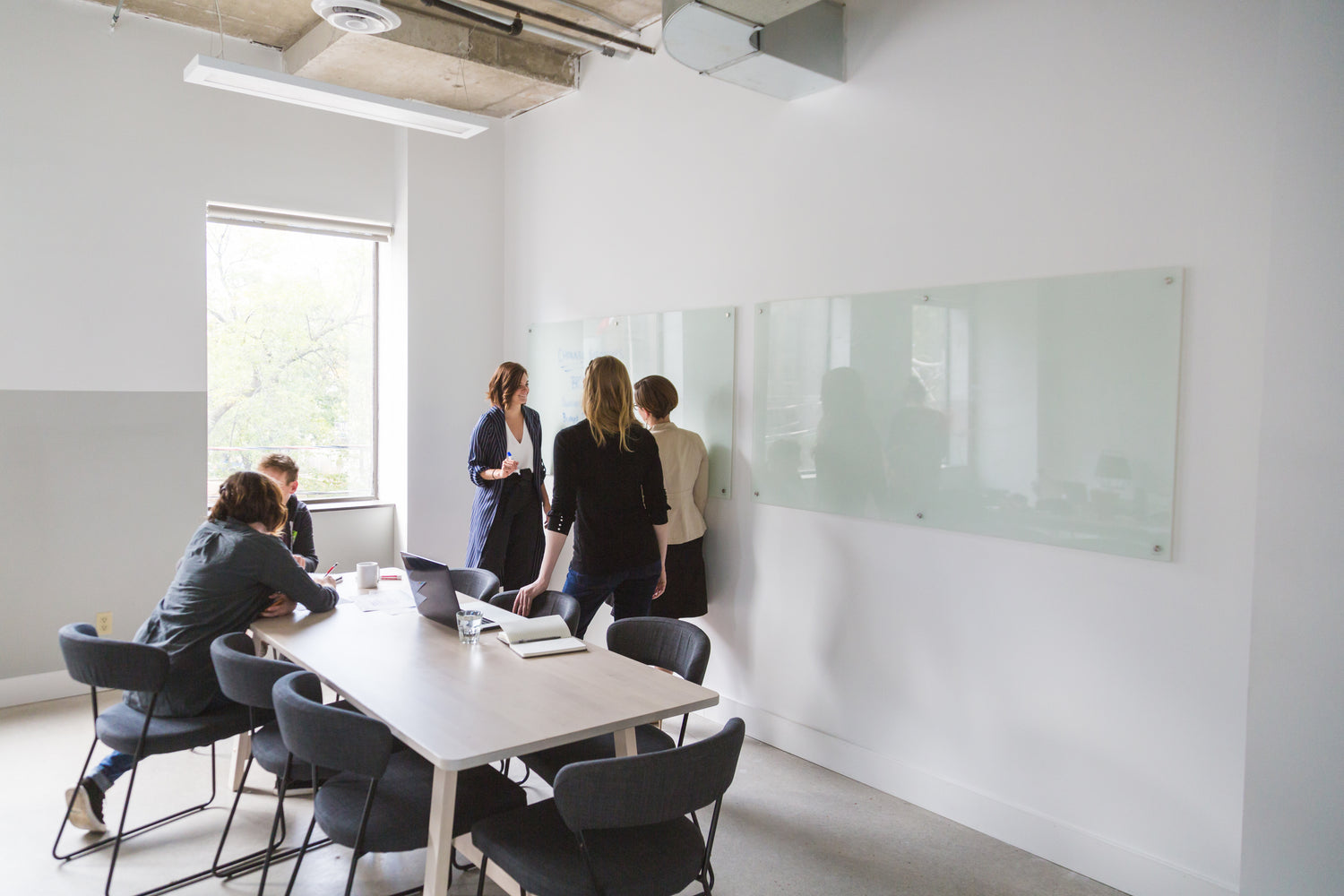 Collaborative meeting at Aptimized: team brainstorming in a bright, modern workspace with whiteboards and natural light.
