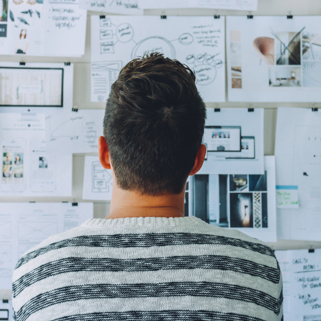 A man observing notes stuck on a notice wall.