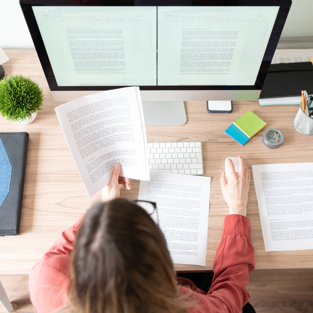 Person reviewing documents at a desk with a computer, representing Aptimized's focus on detail-oriented solutions.